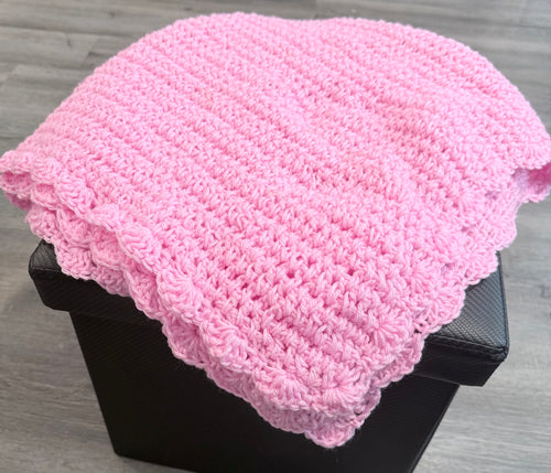 Ballet Pink Baby Crochet Blanket folded on a black ottoman